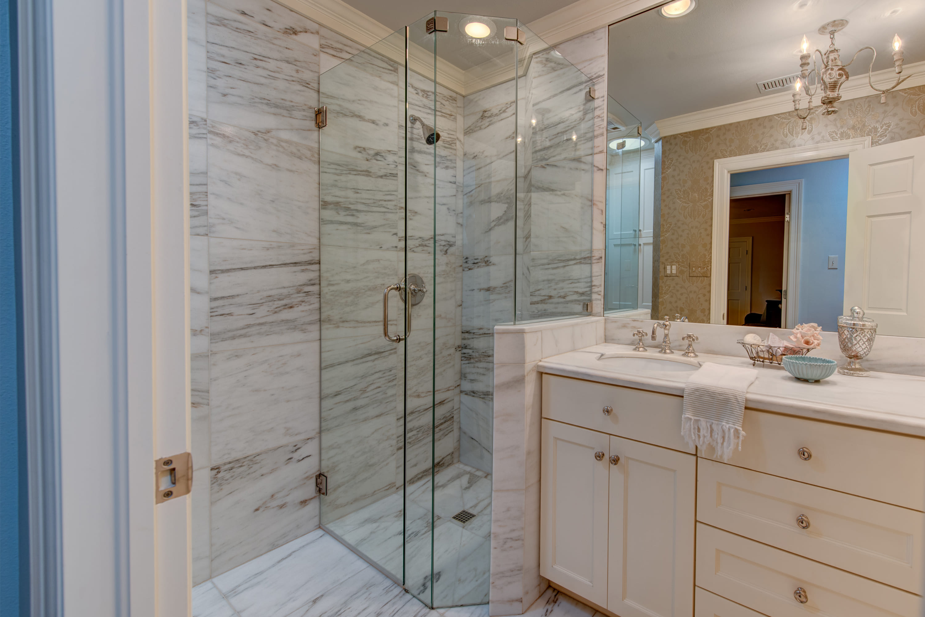 White granite bathroom with a large mirror and a glass shower.