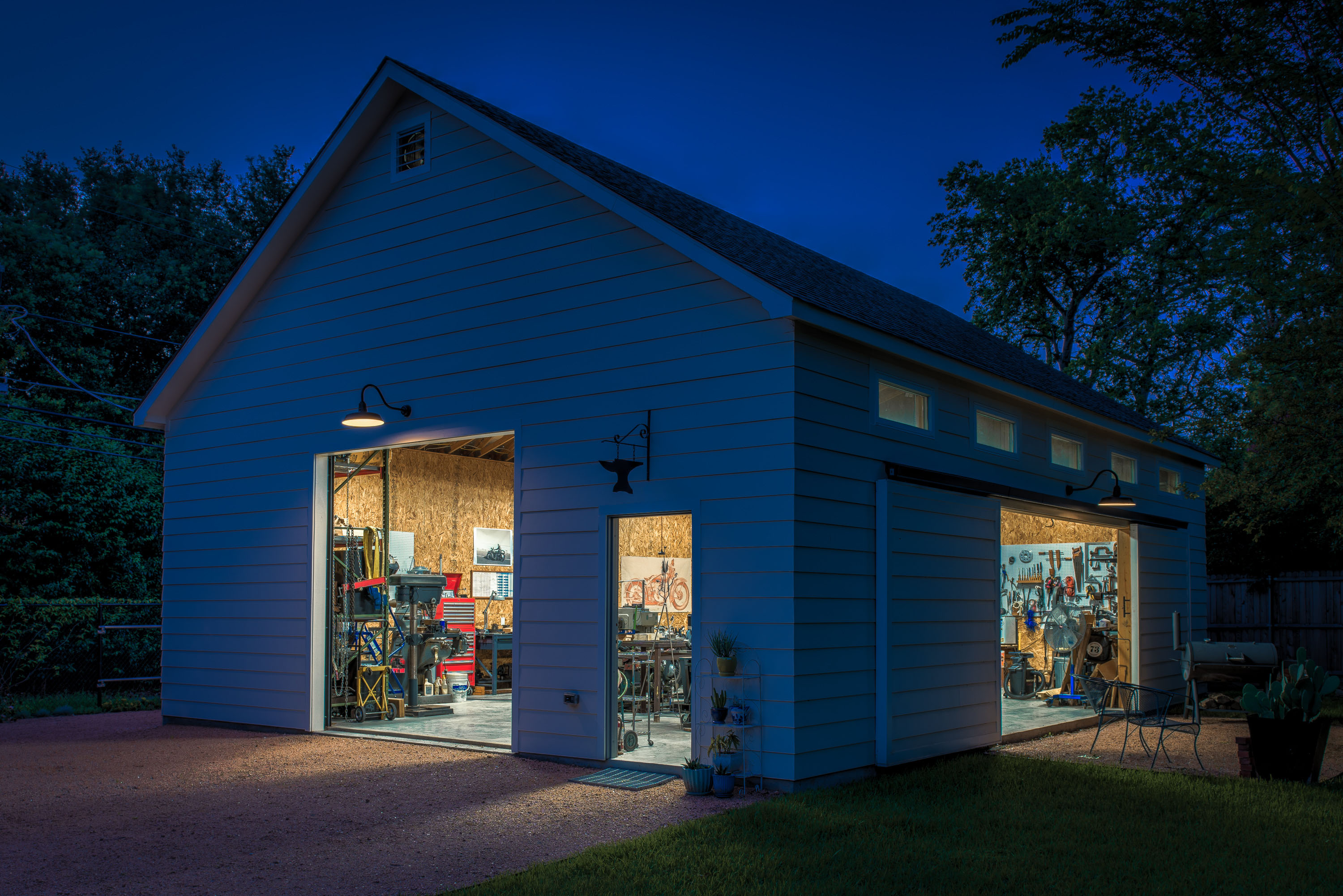 An over-sized, standalone garage at night with light streaming out of the open doors