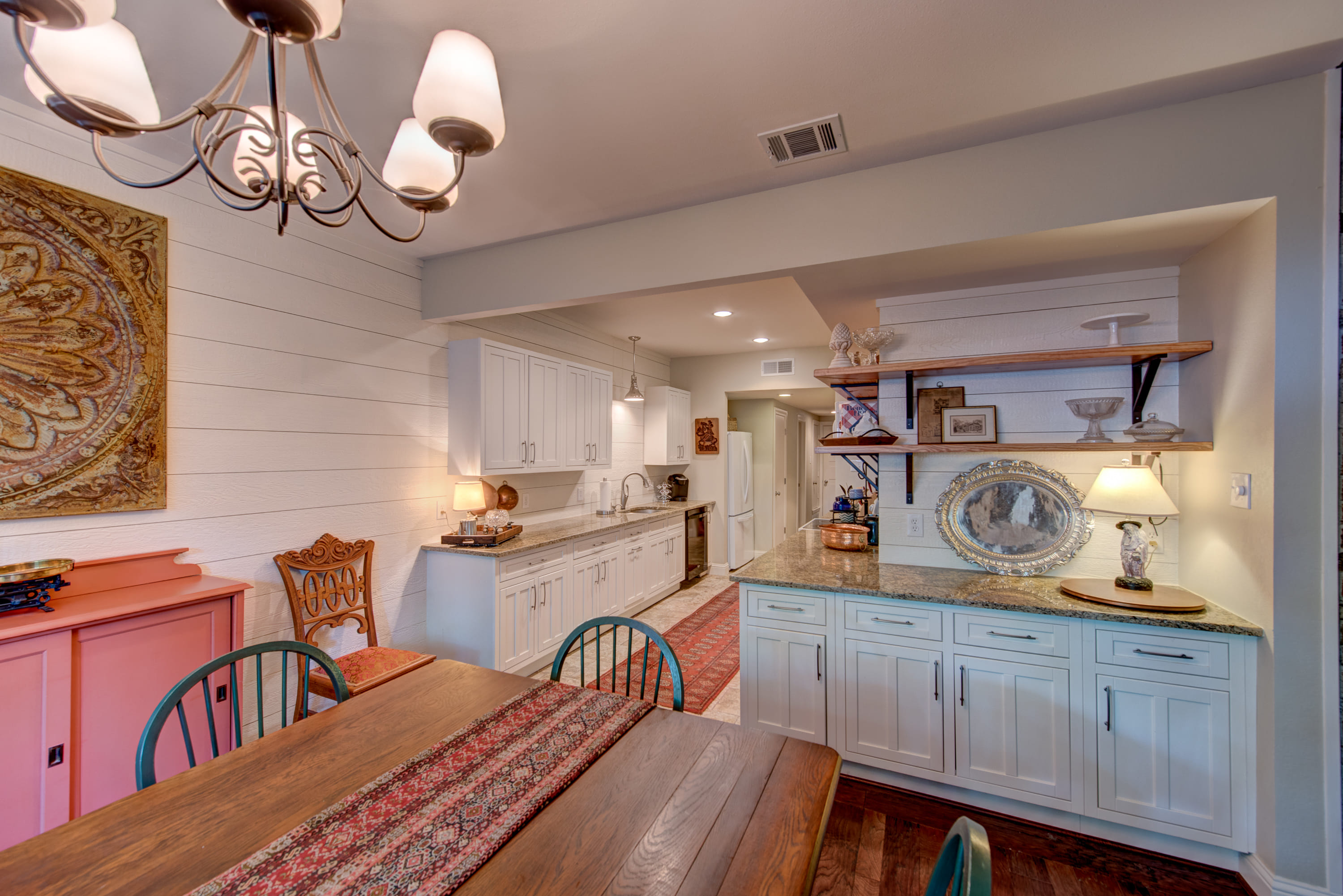 Long kitchen with bright white cabinets and popping pastel colors.