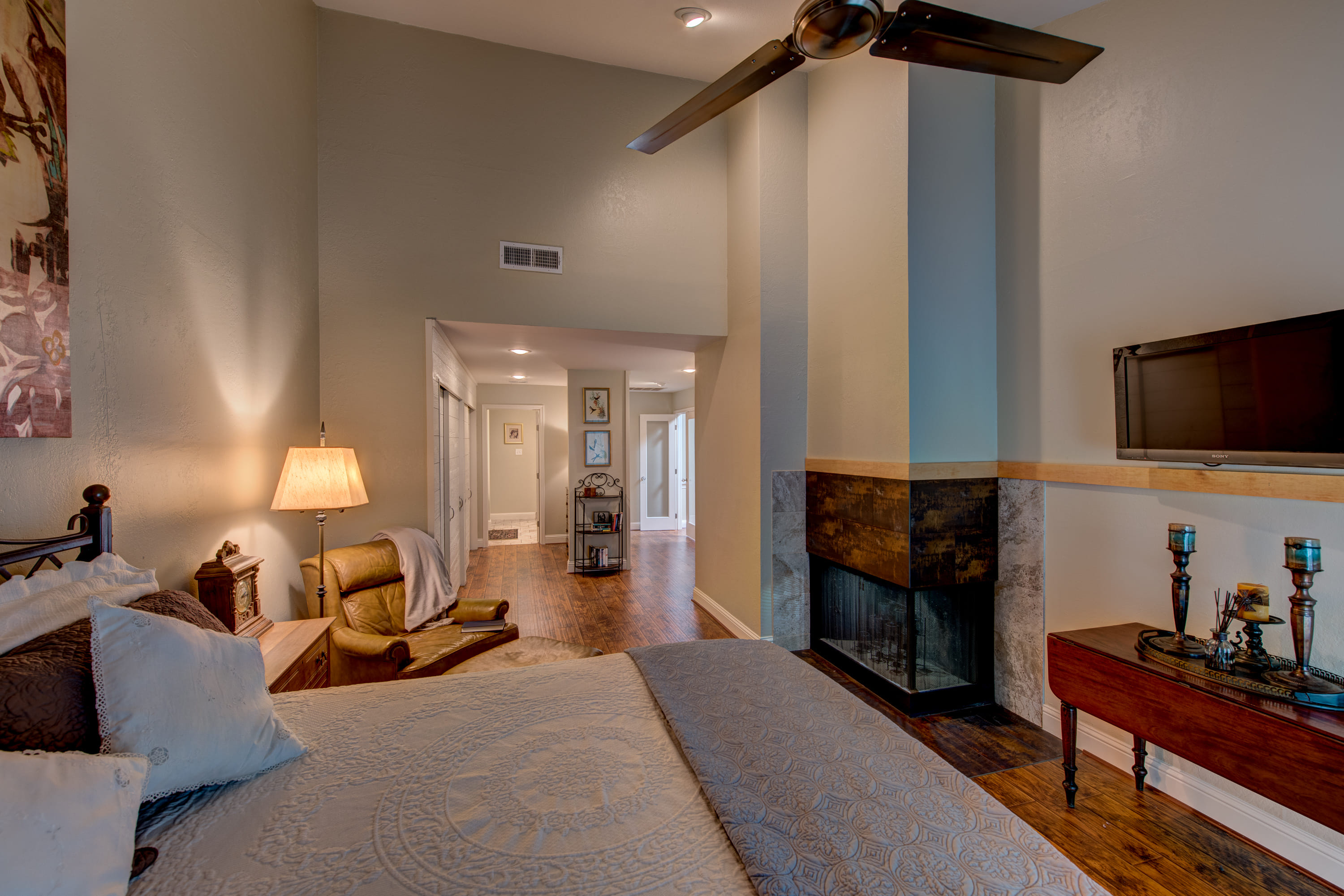 a long bedroom with a fireplace, sliding door closets, and a private bathroom