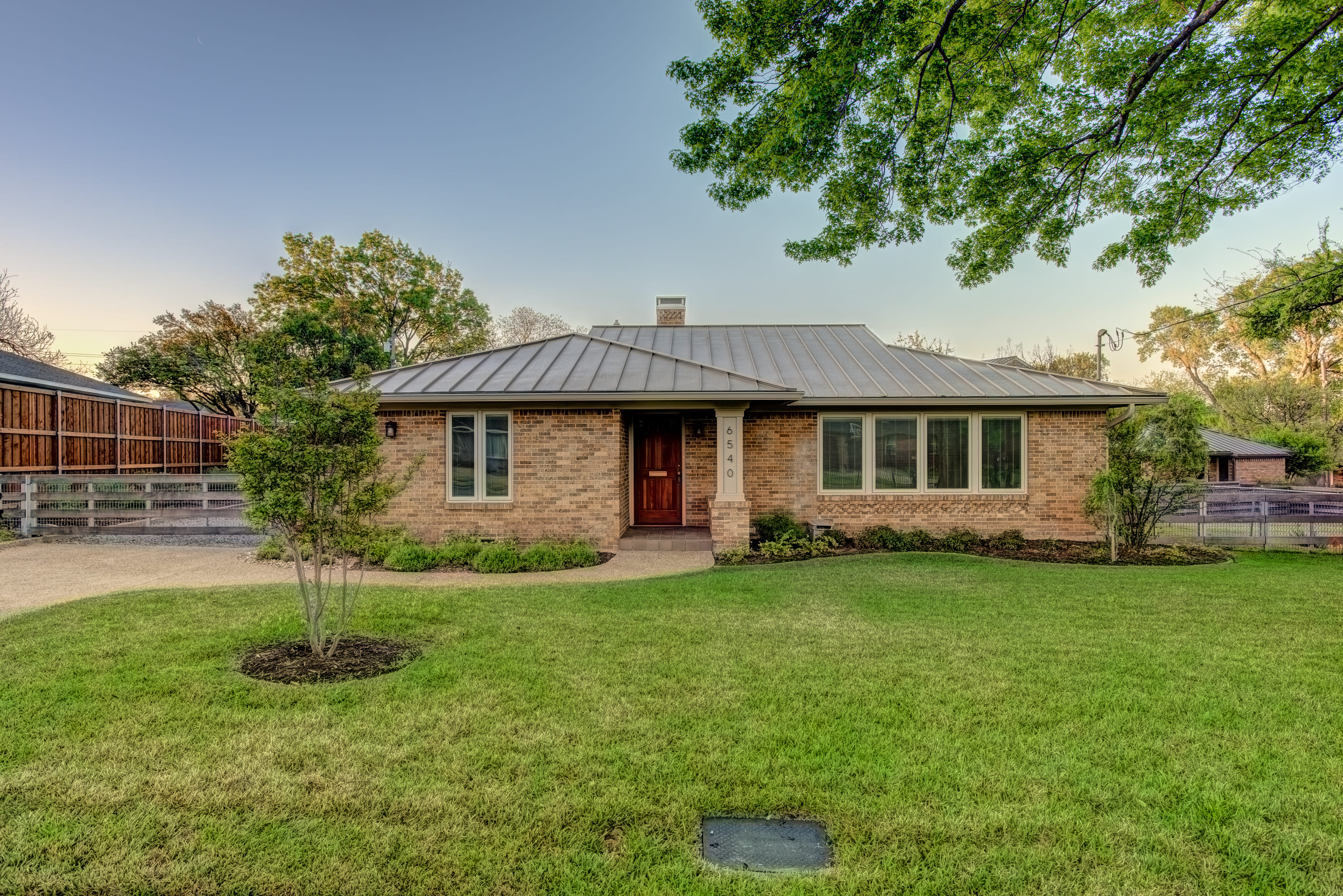 Brick house with a large front yard and a gravel driveway.