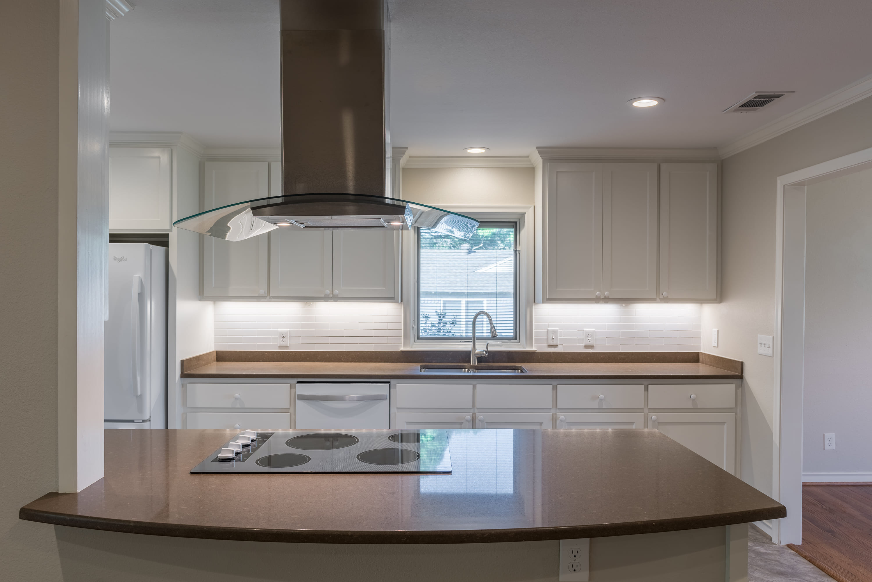 Unfurnished kitchen with a island and stove with overhead hood.
