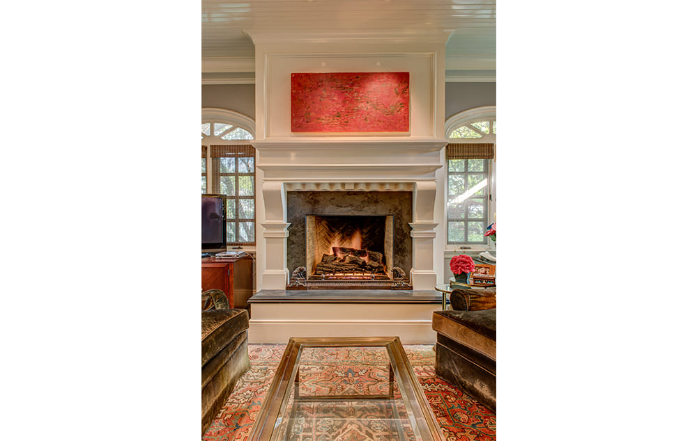 Fireplace with a large mirror and a wooden mantle.