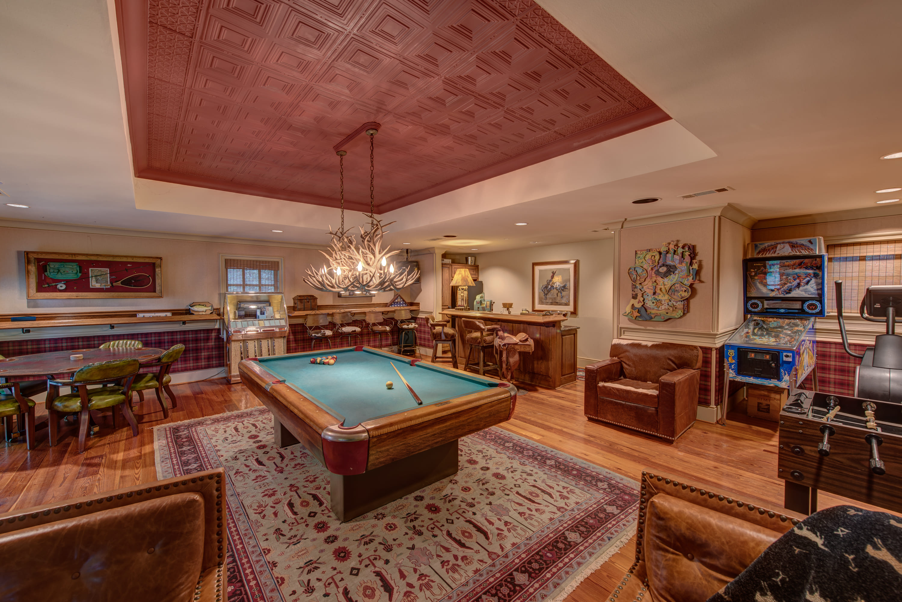 a billiards room with a pool table, bar, and arcade games
